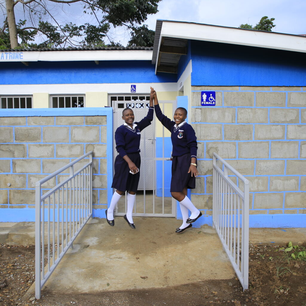 Students high five in front of their new bathroom facilities